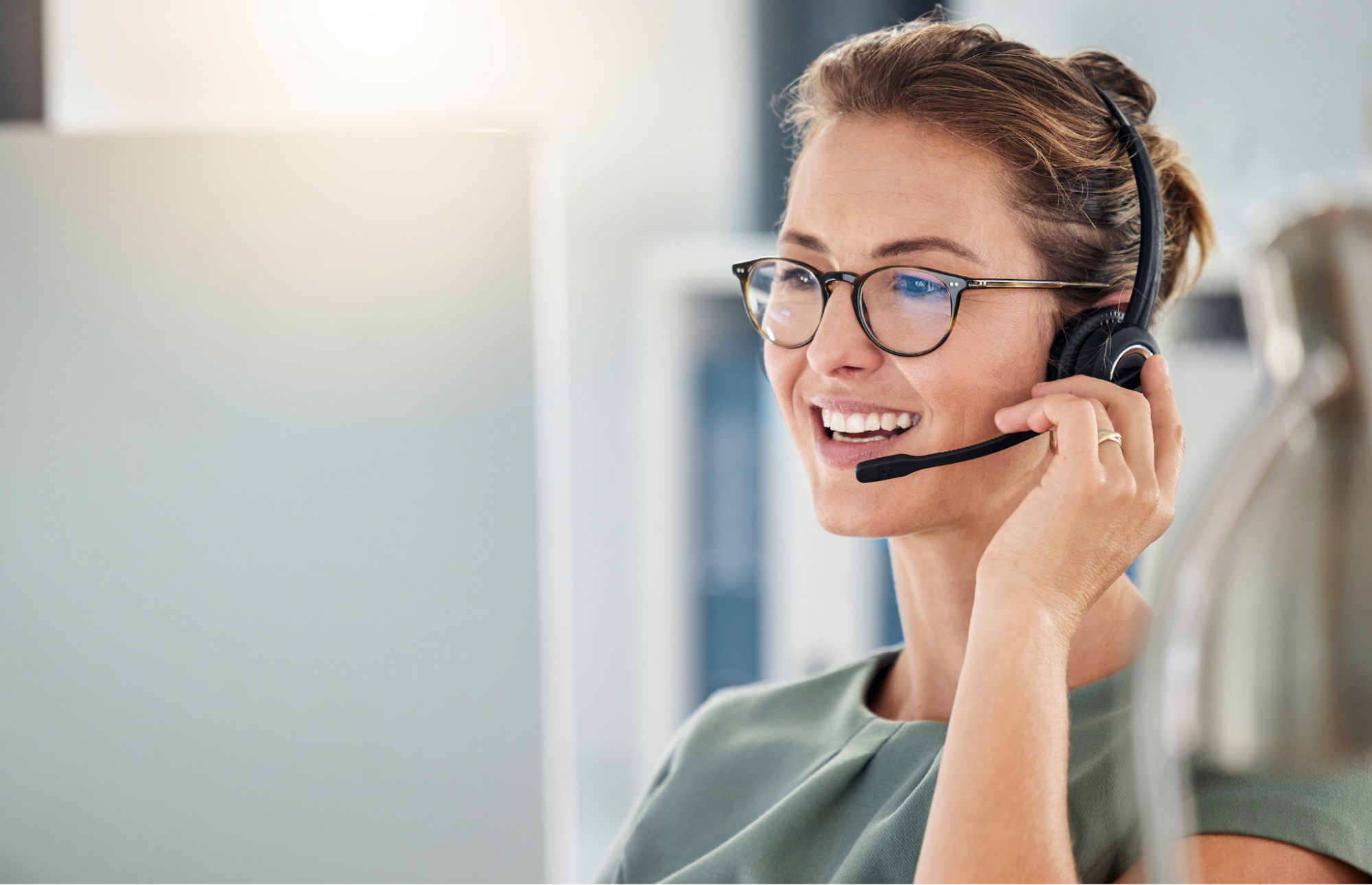 smiling female call center agent wearing headset taking a customer call at her computer desk, illustrating professional after-hours support.